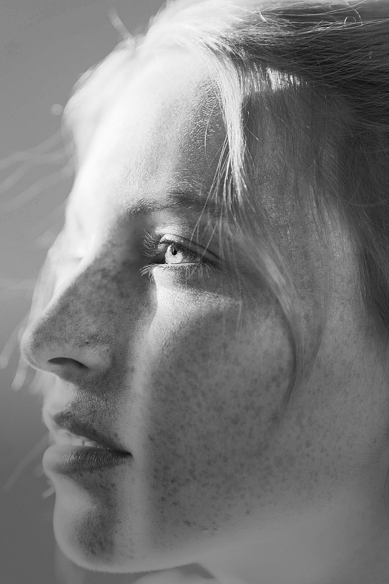 Young woman's profile with freckles in sunlight.