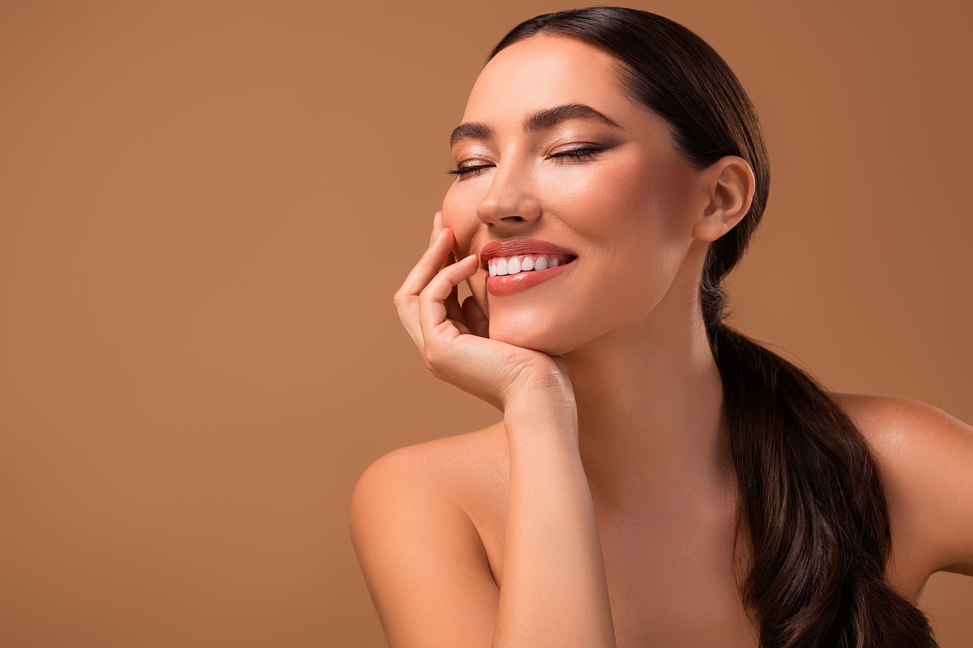 Woman smiling with hand on chin against backdrop at Manor Medspa Phoenix