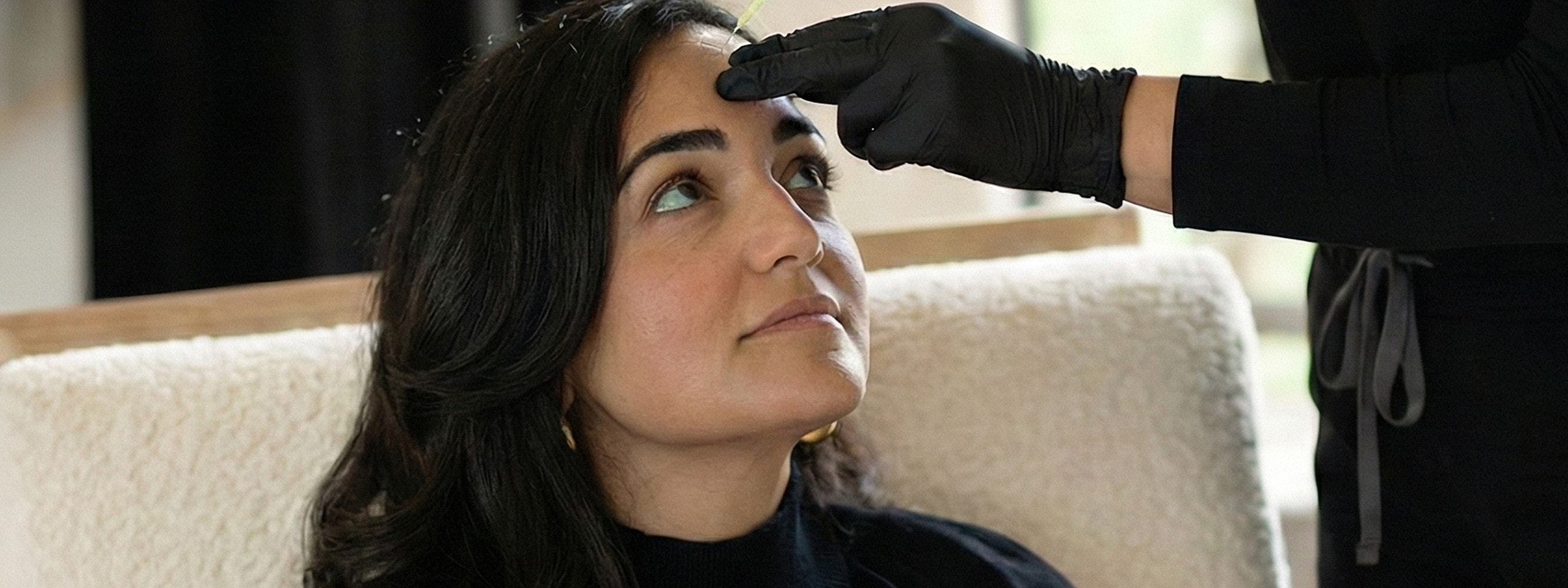 Woman receiving facial treatment with syringe application.